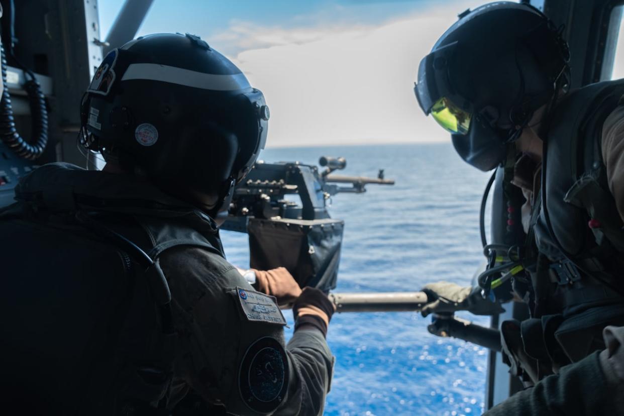 Crew is shown aboard Greywolf, the Coyote helicopter that flies from HMCS Ottawa. Here, they load a .50-calibre machine gun. (Lyza Sale/CBC - image credit)