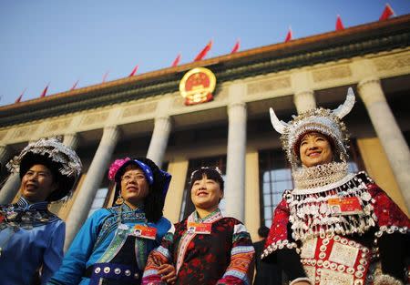 Ethnic minority delegates from Guizhou Province pose for pictures ahead of the opening of the annual full session of the National People's Congress, the country's parliament, in front of the Great Hall of the People at the Tiananmen Square, in Beijing, March 5, 2015. REUTERS/Carlos Barria