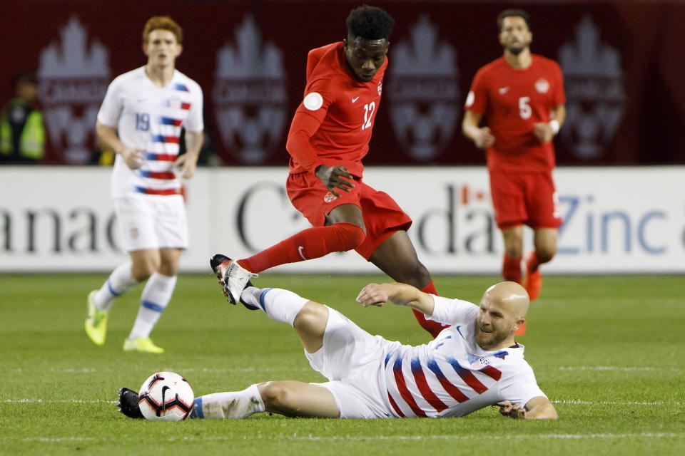 U.S. midfielder Michael Bradley (4) tackles Canada midfielder Alphonso Davies (12) during the first half of a CONCACAF Nations League soccer match Tuesday, Oct. 15, 2019, in Toronto. (Cole Burston/The Canadian Press via AP)