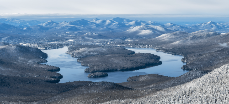 A mostly ice-free Lake Placid contrasts with the wintry landscape around it.