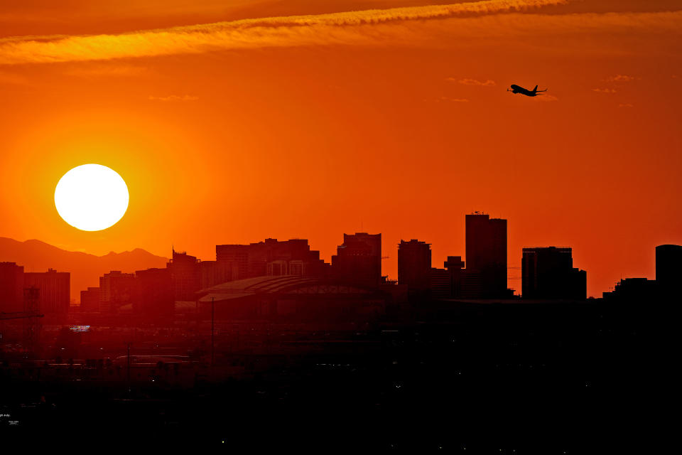 FILE - A jet takes flight from Sky Harbor International Airport as the sun sets over Phoenix, July 12, 2023. The toll of heat associated deaths still being tallied after the hottest summer ever in Arizona’s most populous county has now soared over 360, alarming public health officials. (AP Photo/Matt York, File)