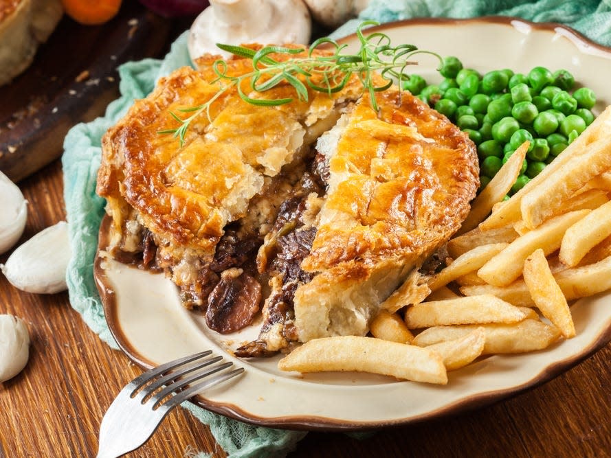 A meat pie with chips and peas.