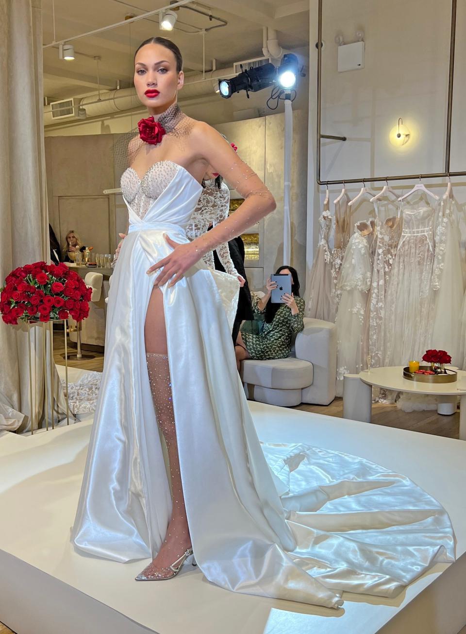 A woman poses in a strapless wedding dress with a high slit.