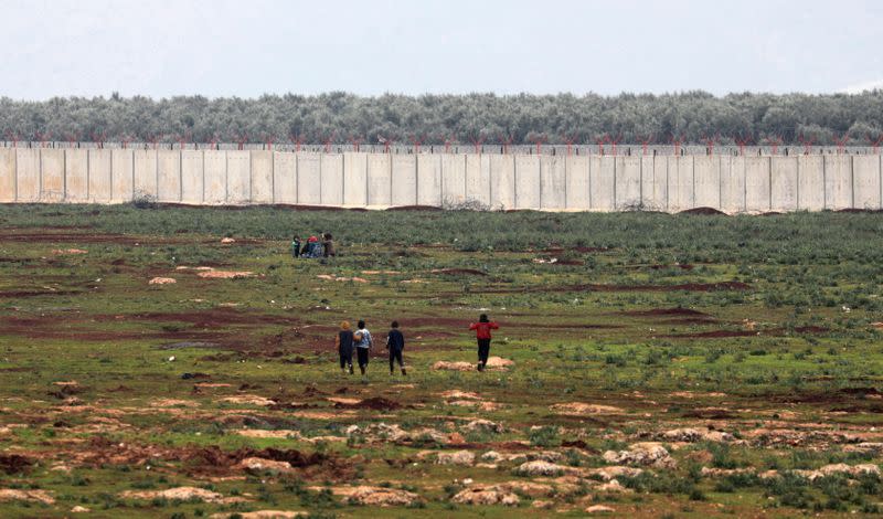 Internally displaced Syrians walk near the wall in Atmah IDP camp, located near the border with Turkey