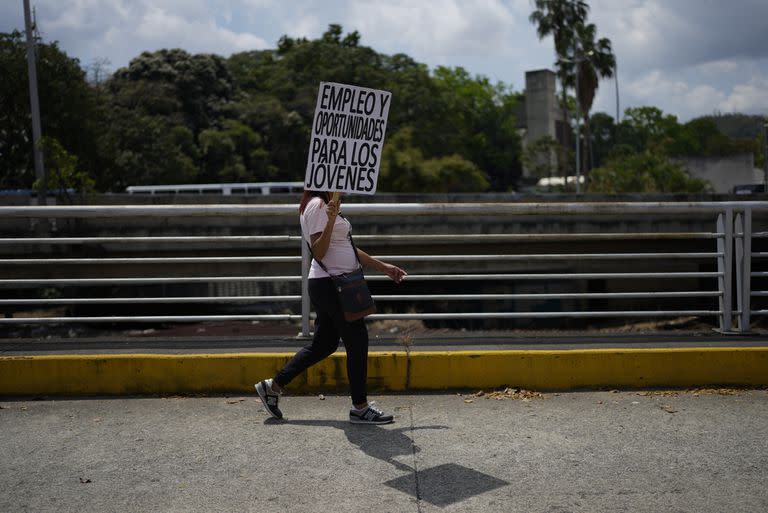 Una mujer lleva un cartel que pide oportunidades laborales en una marcha por el Día Internacional de la Mujer en Caracas, Venezuela, el miércoles 8 de marzo de 2023.