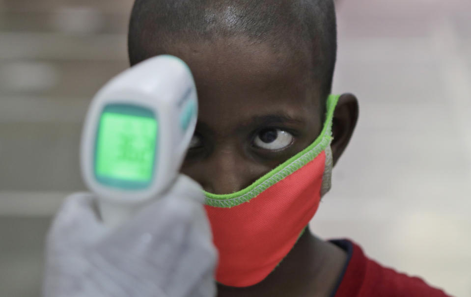 A health worker checks the body temperature of a boy at a medical camp to screen residents for COVID-19 symptoms in Mumbai, India, Friday, July 17, 2020. India crossed 1 million coronavirus cases on Friday, third only to the United States and Brazil, prompting concerns about its readiness to confront an inevitable surge that could overwhelm hospitals and test the country’s feeble health care system. (AP Photo/Rajanish Kakade)