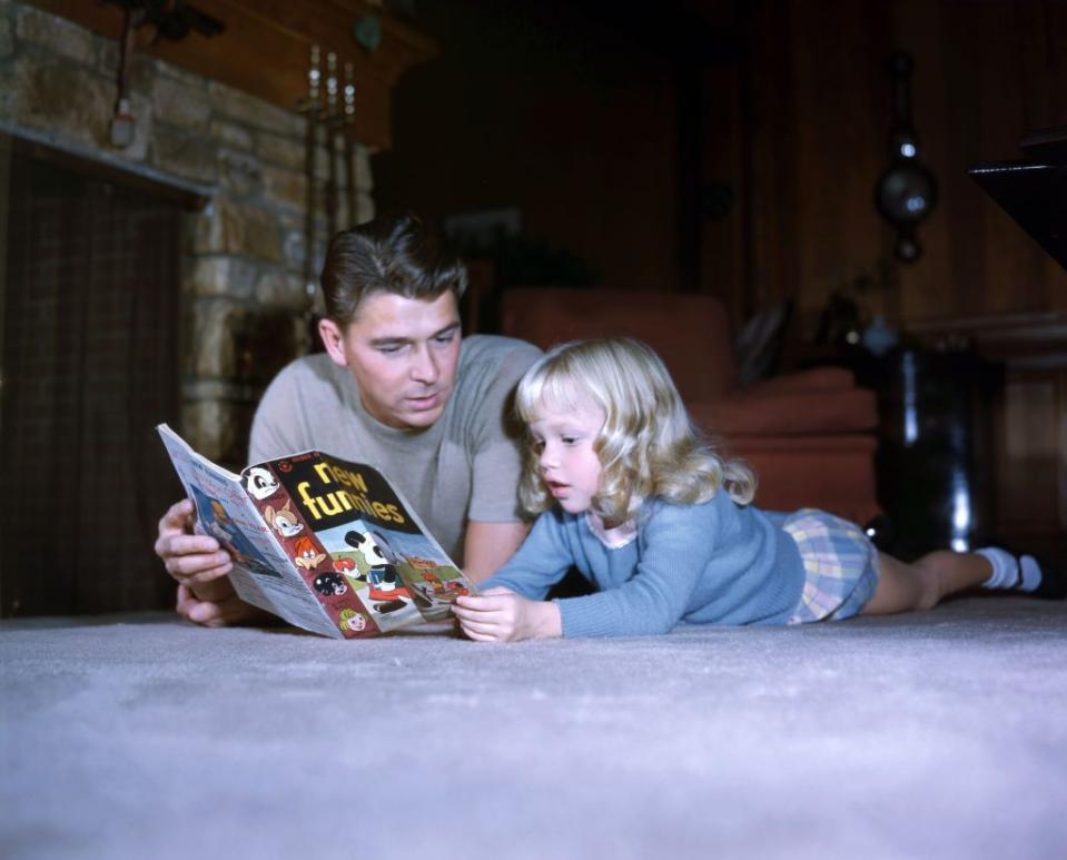 <p>Ronald Reagan lies on the living room floor of his Bel Air home as he reads comics with his daughter Maureen in 1945. </p>