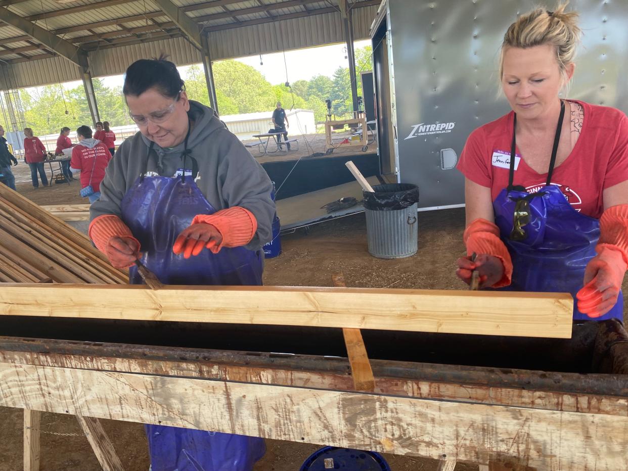 (From left) Maury County teacher Becky Clayborne and Sleep in Heavenly Peace core team member, Jennifer Robbins stain the wood with a cost-effective, team-produced natural stain mixture before building begins on Saturday, April 29 under the Skillington Barn at Maury County Park in Columbia.