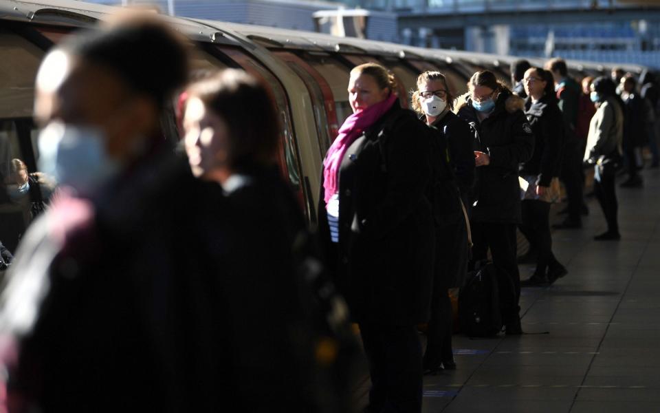 Commuters wait to board a train at Canning Town underground station - Victoria Jones/PA