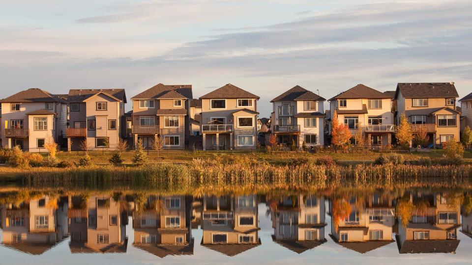 A row of houses reflected in a pond.