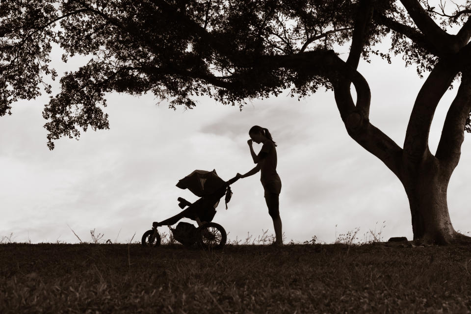 Stressed sad mother pushing stroller.