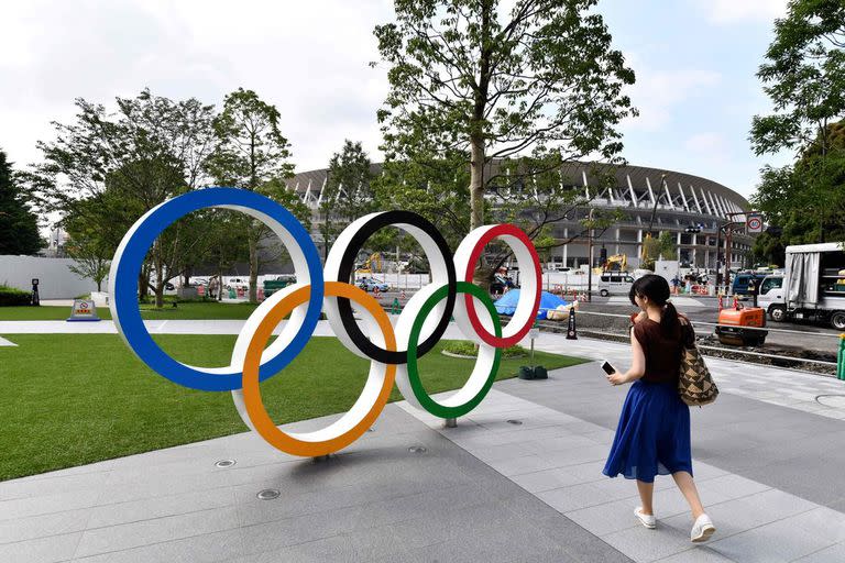Una postal de los anillos de los Juegos Olímpicos. De fondo, el nuevo estadio Nacional en Tokyo, Japón.