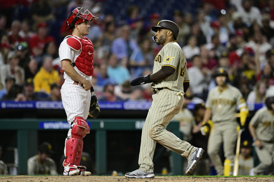 San Diego Padres' Robinson Cano, right, crosses home plate to score a run on a hit by Trent Grisham in front of Philadelphia Phillies' J.T. Realmuto during the seventh inning of a baseball game, Tuesday, May 17, 2022, in Philadelphia. (AP Photo/Derik Hamilton)