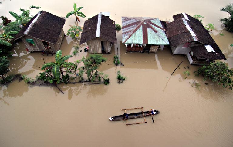 Residents paddle past submerged houses after flooding brought about by heavy rains in the outskirts of Butuan City, Agusan del norte province, on the southern island of Mindanao on January 13, 2014