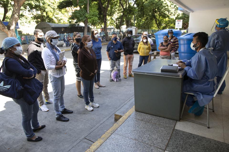 El doctor Wilfredo Sifontes habla con familiares que quieren visitar a pacientes internados en la unidad del COVID-19 del Hospital José Gregorio Hernández de Caracas el 4 de septiembre del 2020. Los parientes a veces tienen que esperar horas afuera para poder llevarles comida, ropa limpia y bañar a sus familiares. (AP Photo/Ariana Cubillos)