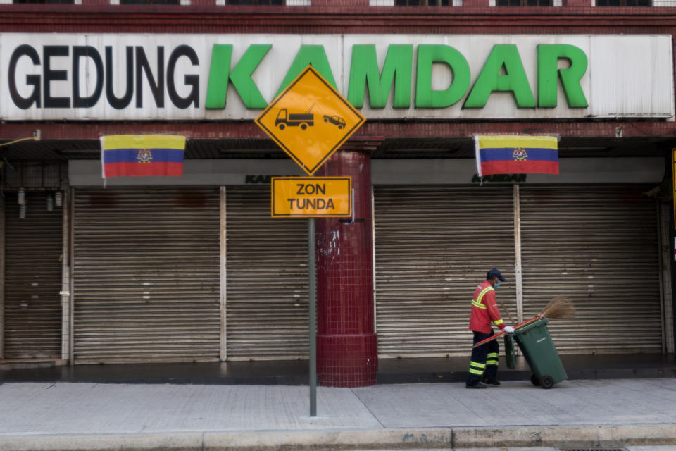 A cleaner walks past a closed shop along Kuala Lumpur's Jalan Tunku Abdul Rahman on 18 March 2020, the first day of the Movement Control Order. (PHOTO: Fadza Ishak for Yahoo Malaysia)