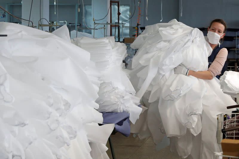 An employee carries protective suits at the Textile-Contact company's factory in Chernihiv