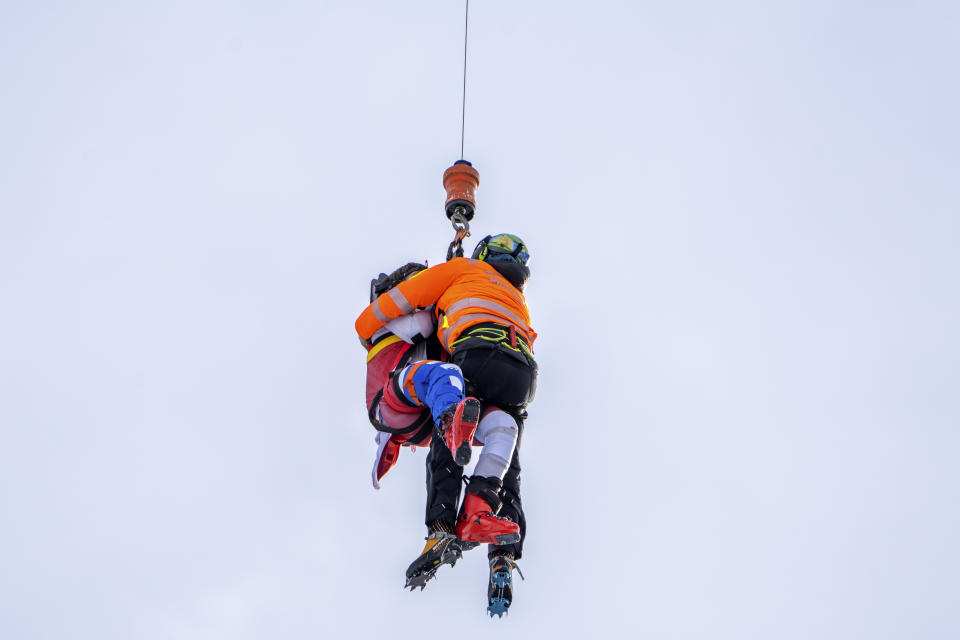 Austria's Marco Schwarz, left, is airlifted after crashing during an alpine ski, men's World Cup downhill race, in Bormio, Italy, Thursday, Dec. 28, 2023. Schwarz appeared to hurt his right knee in a left turn before getting thrown off the course halfway through his run. He was taken off the hill by a helicopter. (AP Photo/Giovanni Zenoni)