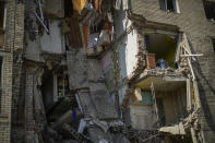 Debris hangs from a residential building heavily damaged in a Russian bombing in Bakhmut, eastern Ukraine, Tuesday, May 24, 2022. The town of Bakhmut has been coming under increasing artillery strikes, particularly over the last week, as Russian forces try to press forward to encircle the city of Sieverodonetsk to the northeast. (AP Photo/Francisco Seco)