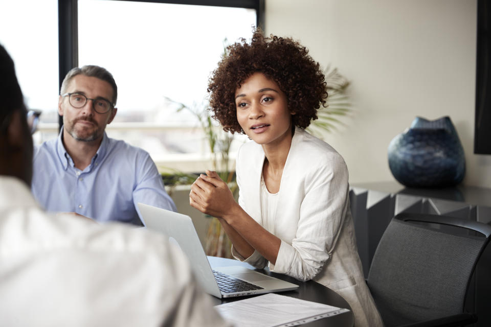 Millennial black businesswoman listening to colleagues at a corporate business meeting, close up