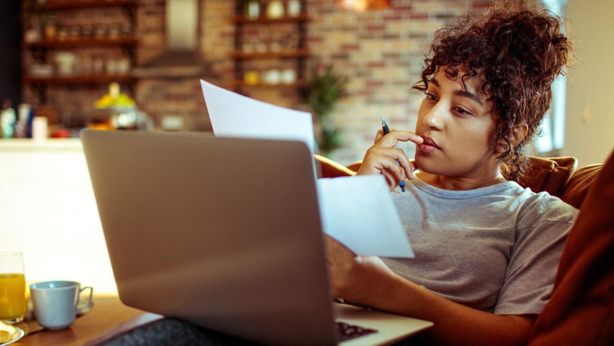 young woman using a laptop and doing her bills at home.