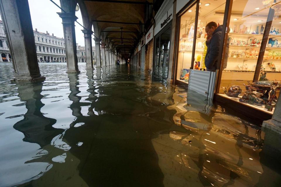 A shopkeeper looks out at the rising waters in St. Mark's Square during a high tide, in Venice, Italy.