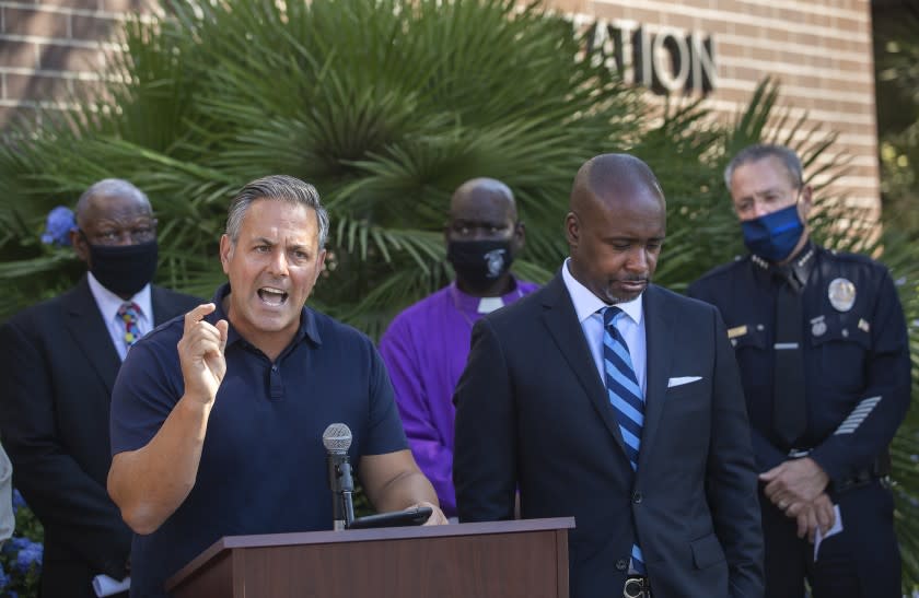 LOS ANGELES, CA - OCTOBER 02, 2020: Los Angeles City Councilman Joe Buscaino, left, addresses the media during a press conference outside the Southeast Community Police Station to discuss an increase in violent crime in South Los Angeles. 2nd from right is Los Angeles City Councilman Marqueece Harris-Dawson and at right is LAPD Police Chief Michel Moore. (Mel Melcon / Los Angeles Times)