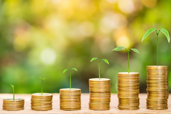 Stacks of coins growing successively taller with seedlings sprouting out of each column.