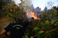 A firefighter tries to extinguish a fire in Kryoneri area, northern Athens, Greece, Thursday, Aug. 5, 2021. Wildfires rekindled outside Athens and forced more evacuations around southern Greece Thursday as weather conditions worsened and firefighters in a round-the-clock battle stopped the flames just outside the birthplace of the ancient Olympics. (AP Photo/Michael Varaklas)