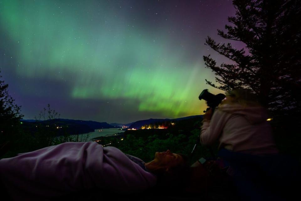 LATOURELL, OREGON - MAY 11: Kathryn Richer (left) and her friend Andrea gaze upon the Northern Lights at Chanticleer Point Lookout on the Columbia River Gorge in the early morning hours of May 11, 2024 in Latourell, Oregon. Places as far south as Alabama and parts of Northern California were expected to see the aurora borealis, also known as the northern lights from a powerful geomagnetic storm that reached Earth. (Photo by Mathieu Lewis-Rolland/Getty Images)