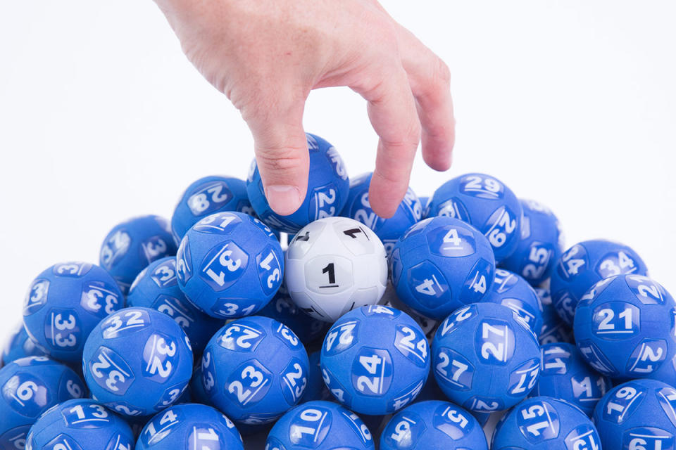 Lotto balls with a hand going to pick the number 1 up