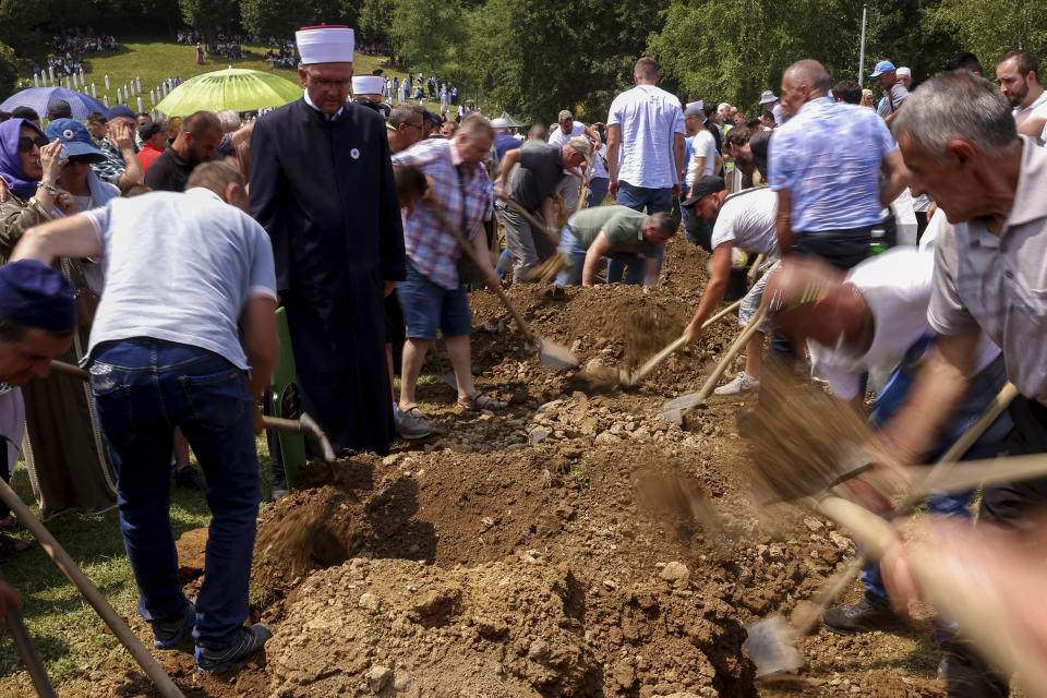Bosnian muslim men cover the graves with soil during the mass funeral of 30 newly identified victims of the Srebrenica Genocide in Potocari, Bosnia, Tuesday, July 11, 2023. Thousands gather in the eastern Bosnian town of Srebrenica to commemorate the 28th anniversary on Monday of Europe's only acknowledged genocide since World War II. (AP Photo/Armin Durgut)