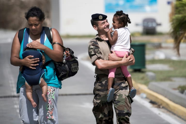 A family is escorted by a French soldier at the Grand-Case Esperance airport on the French Caribbean island of Saint-Martin