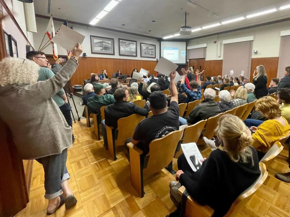 Attendees hold up signs at the San Luis Obispo City Council on Nov. 7, 2023, as speakers share how parking challenges were impacting the downtown. Kaytlyn Leslie/kleslie@thetribunenews.com