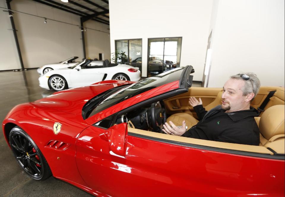 In this Wednesday, March, 26, 2014 photo, Steve Briscoe, vice president, Industrial Air Centers, Inc., reacts as he starts the motor of a 2014 Ferrari California displayed for rent at the Enterprise Exotic Car Collection showroom near Los Angeles International Airport. (AP Photo/Damian Dovarganes)
