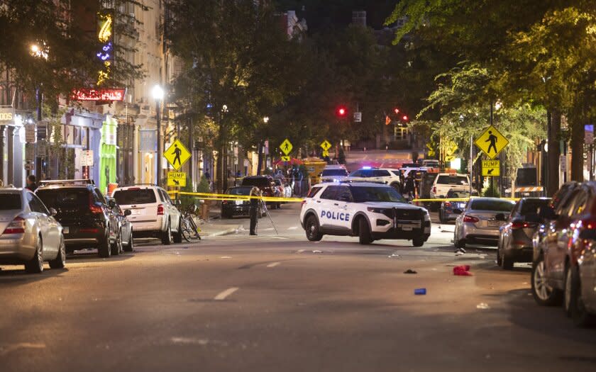 Cincinnati police officer investigate the scene early Sunday, Aug. 7, 2022, in Cincinnati, following an overnight shooting. At least nine people were wounded — none critically — in a shooting outside a Cincinnati bar early Sunday, police said. (Liz Dufour/The Cincinnati Enquirer via AP)