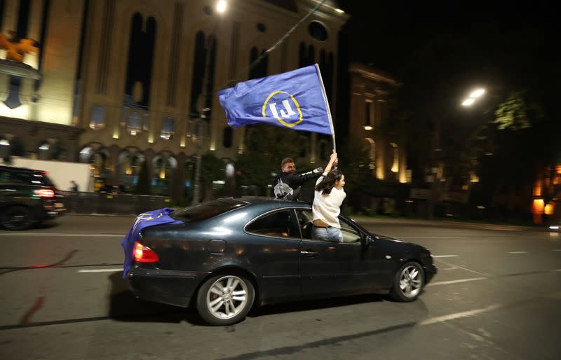 Supporters of the ruling Georgian Dream party wave a flag from a car after exit polls were announced during parliamentary election, in Tbilisi