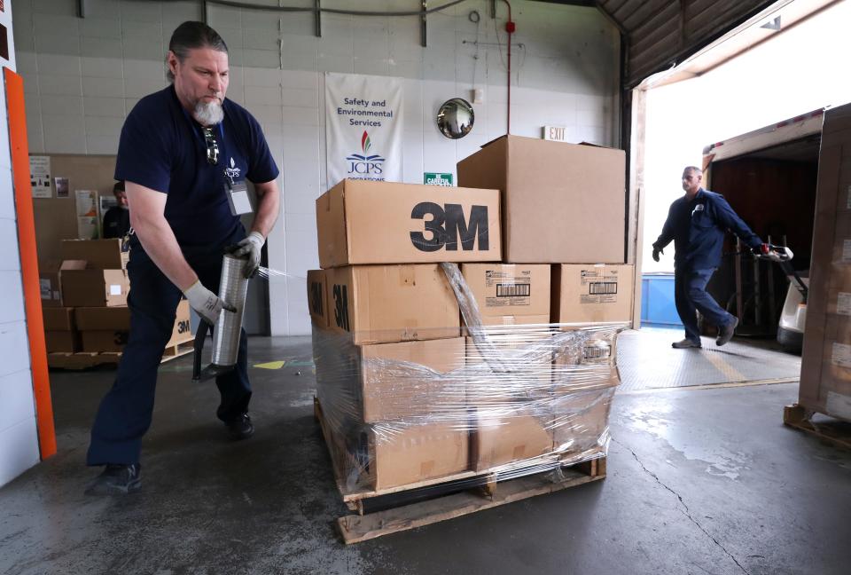 Layman Leasor, a JCPS employee, wraps boxes of personal protective equipment in plastic on a shipping dock at the Young Building on Crittenden Drive in Louisville, Ky. on Mar. 26, 2020.  The school system is donating 40,000 items, including masks and gloves to the Louisville Metro Public Health Department to assist in their efforts to control the spread of the coronavirus outbreak.