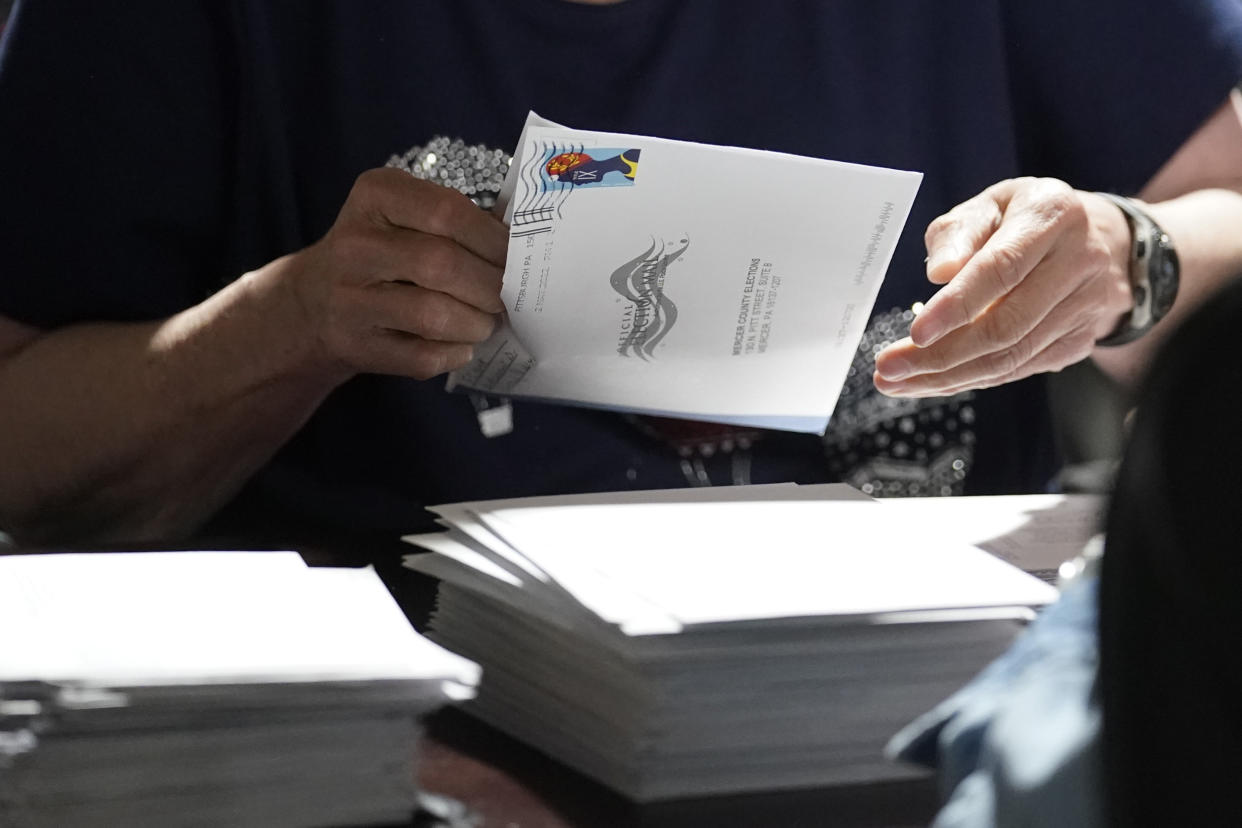 An election worker removes a mail-in ballot from an envelope.