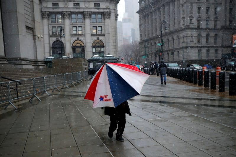 A man walks beneath an umbrella through falling snow in lower Manhattan in New York