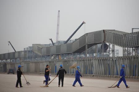 Workers walk in front of the Hebei Zongheng Iron and Steel plant that is under construction at the Tangshan Fengnan Economic Development Zone, Hebei province, China, August 22, 2018. REUTERS/Thomas Peter