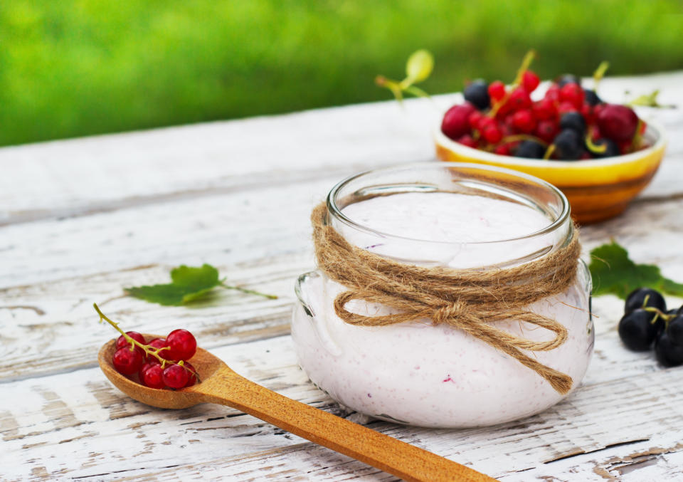 Yogurt in a jar and a saucer with white wooden berries on a table in the fresh air