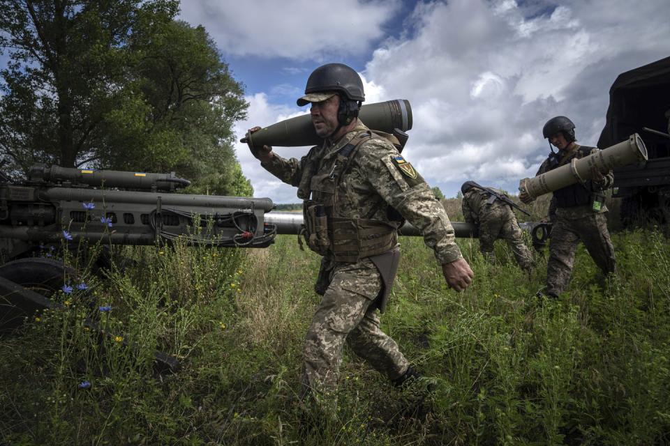 A Ukrainian serviceman carries an artillery shell before firing at Russian positions from a U.S.-supplied howitzer in Kharkiv region, Ukraine, on July 14, 2022. (AP Photo/Evgeniy Maloletka)
