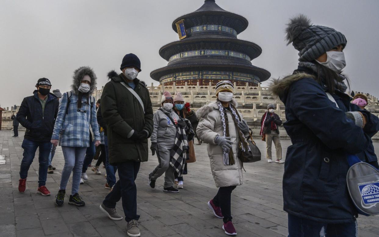 Visitors wear protective masks as they tour the grounds of the Temple of Heaven in Beijing - Getty Images AsiaPac