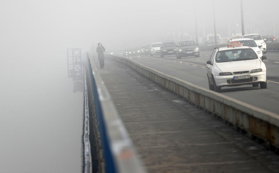 A girl walks across a bridge in Belgrade, Serbia, Wednesday, Jan. 15, 2020. Serbia's government on Wednesday called an emergency meeting, as many cities throughout the Balkans have been hit by dangerous levels of air pollution in recent days, prompting residents' anger and government warnings to stay indoors and avoid physical activity. (AP Photo/Darko Vojinovic)