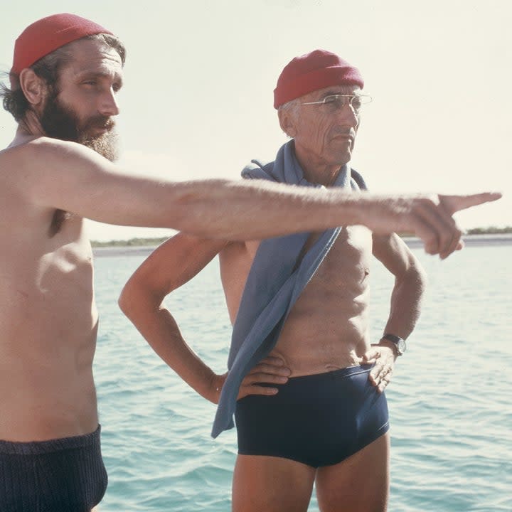 Phillippe and Jacques Cousteau standing on the deck of a boat in red caps