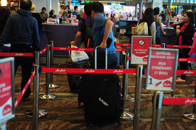 Passengers queue at an AirAsia check-in counter inside terminal 1 at Changi international airport in Singapore