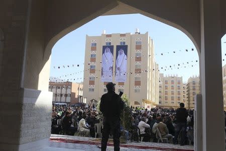 A member of Palestinian security forces loyal to Hamas stands guard as posters depicting Qatar's former Emir Sheikh Hamad bin Khalifa al-Thani (R) and Emir of Qatar Tamim bin Hamad al-Thani are seen on a building during the opening ceremony of Qatari-funded construction project "Hamad City", in Khan Younis in the southern Gaza Strip January 16, 2016. REUTERS/Ibraheem Abu Mustafa