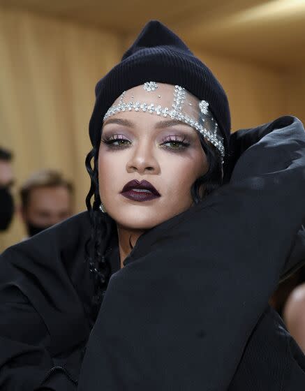 A woman in a black puffy dress, dark hood and lace cap with crystal details poses dramatically