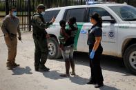 A U.S. CBP officer talks with a migrant seeking asylum in the U.S. near the International Bridge between Mexico and the U.S., in Del Rio